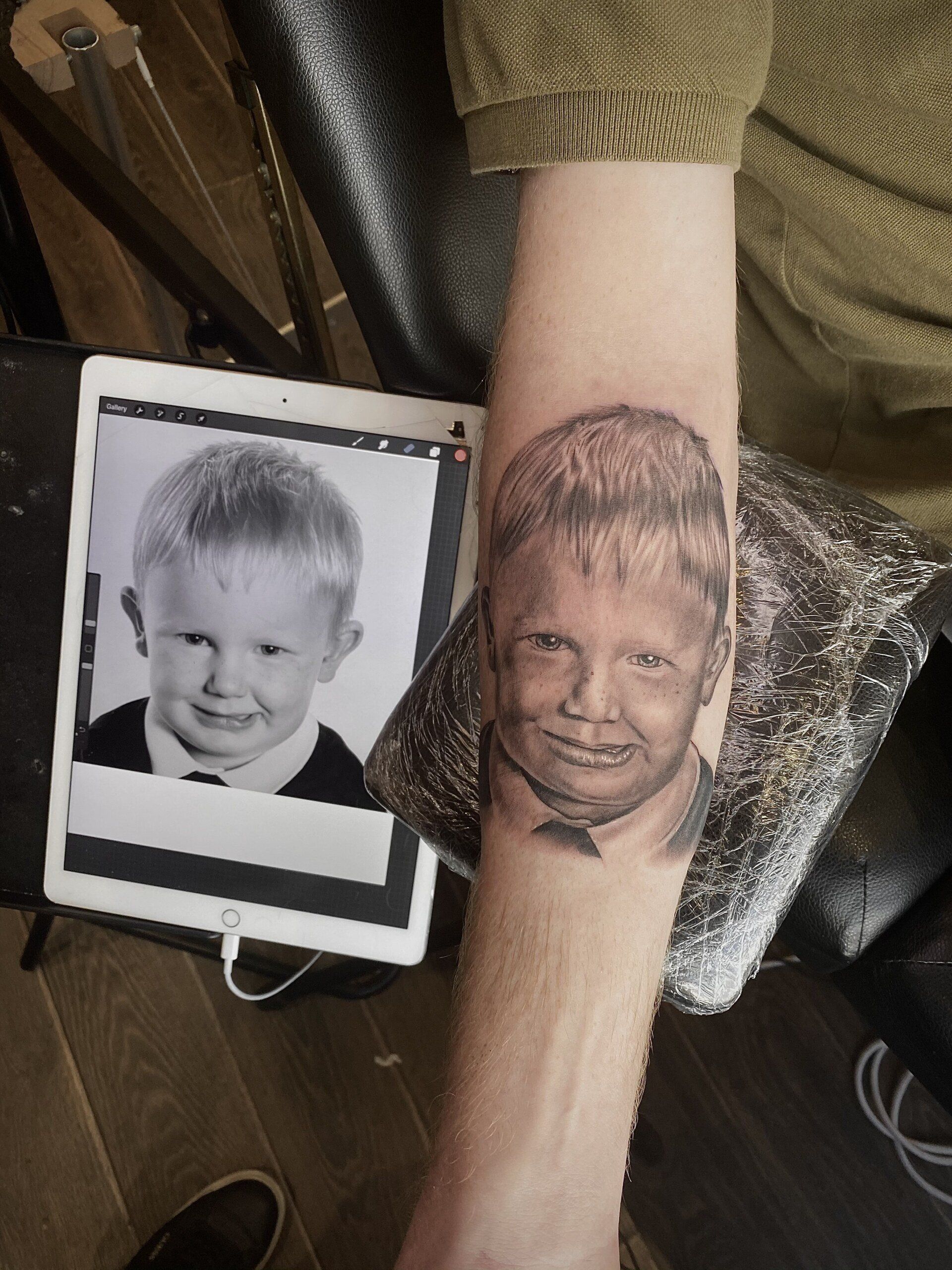 A man has a tattoo of a child's face on his arm